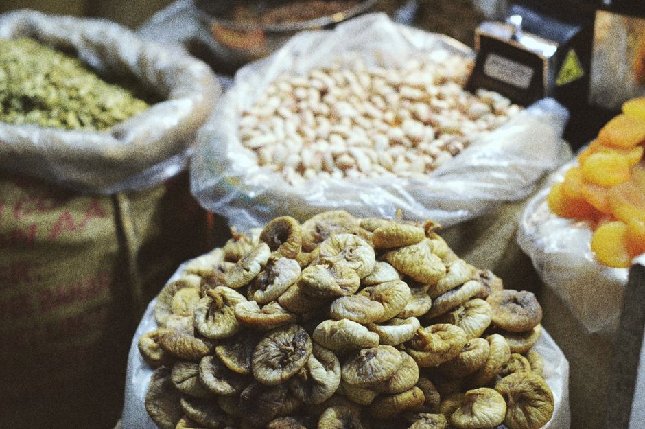Assorted dried fruits and nuts in bags at a market, showcasing vibrant textures.